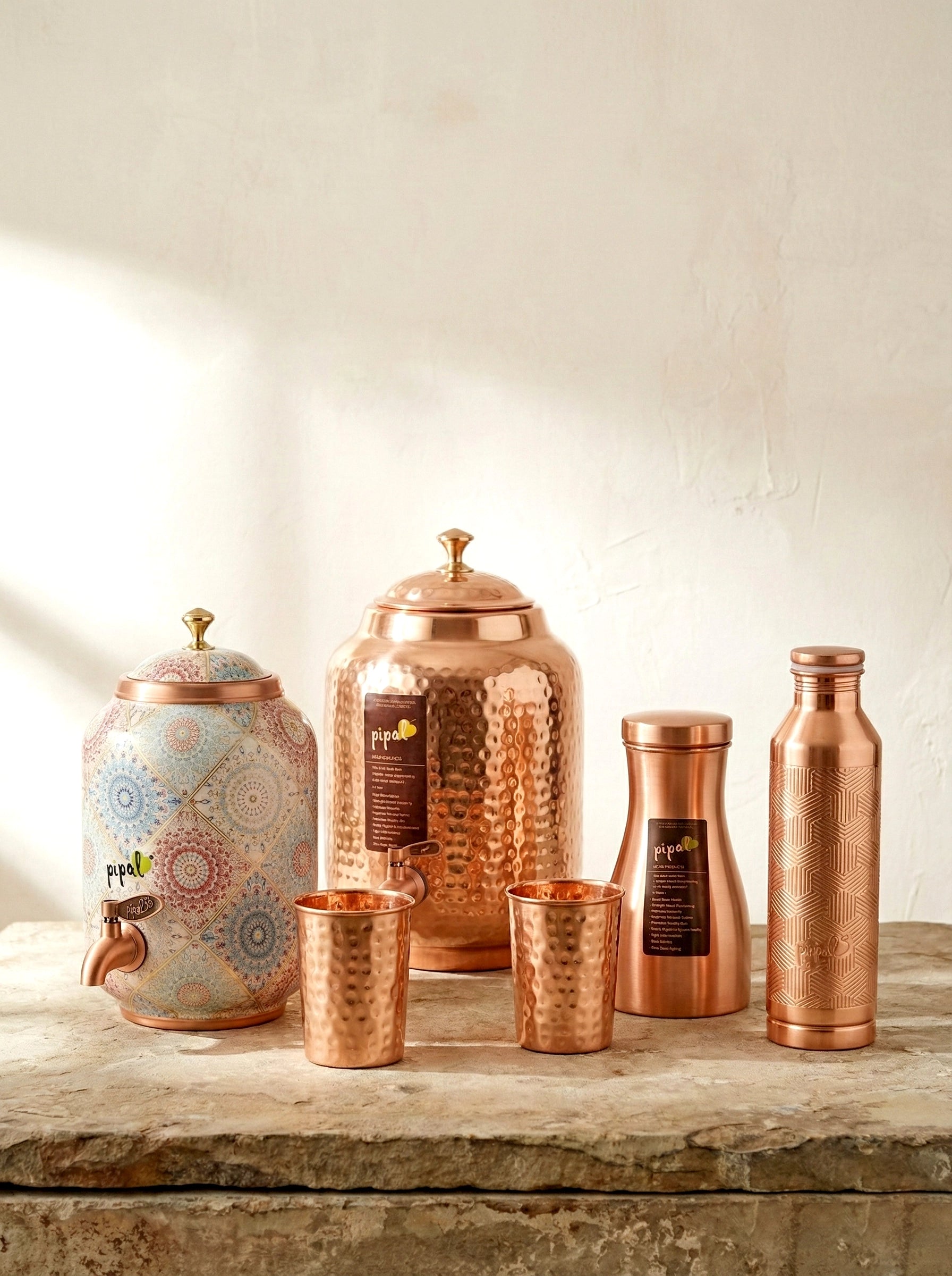 Set of copper kitchenware including jars, bottles, and cups on a stone surface.