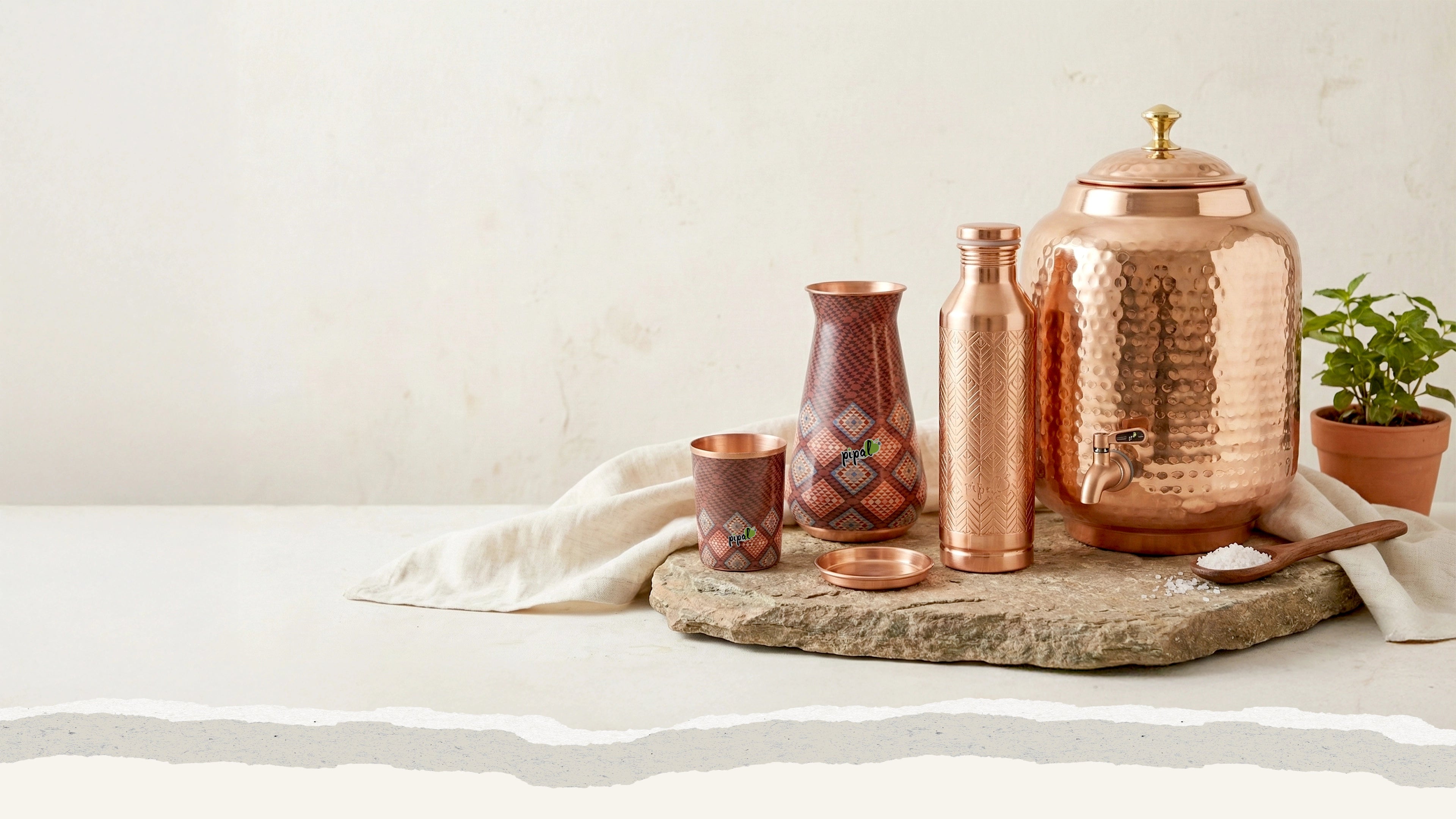 Copper kitchenware set on a stone block and linen cloth with a white background
