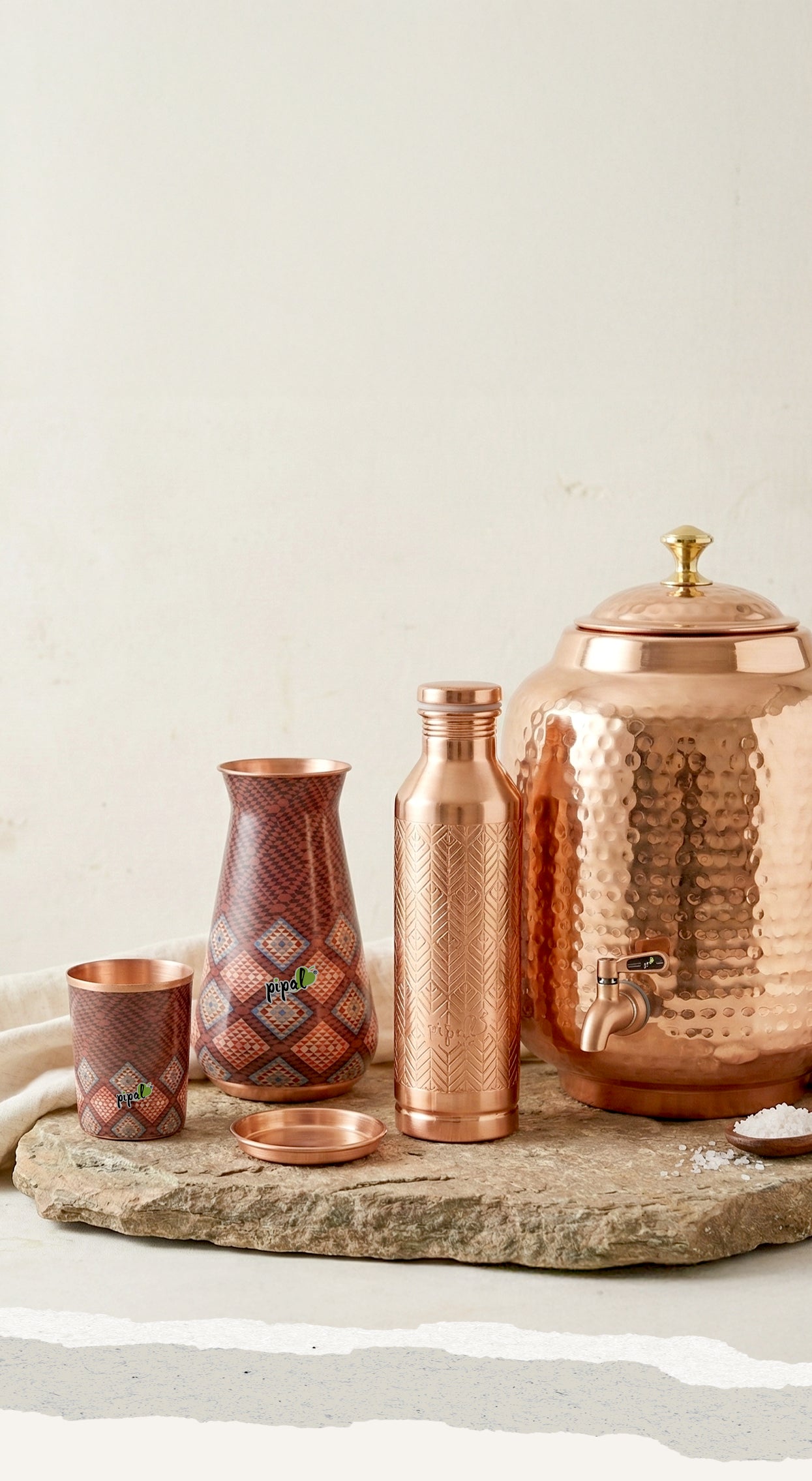 Copper kitchenware set on a stone block and linen cloth with a white background