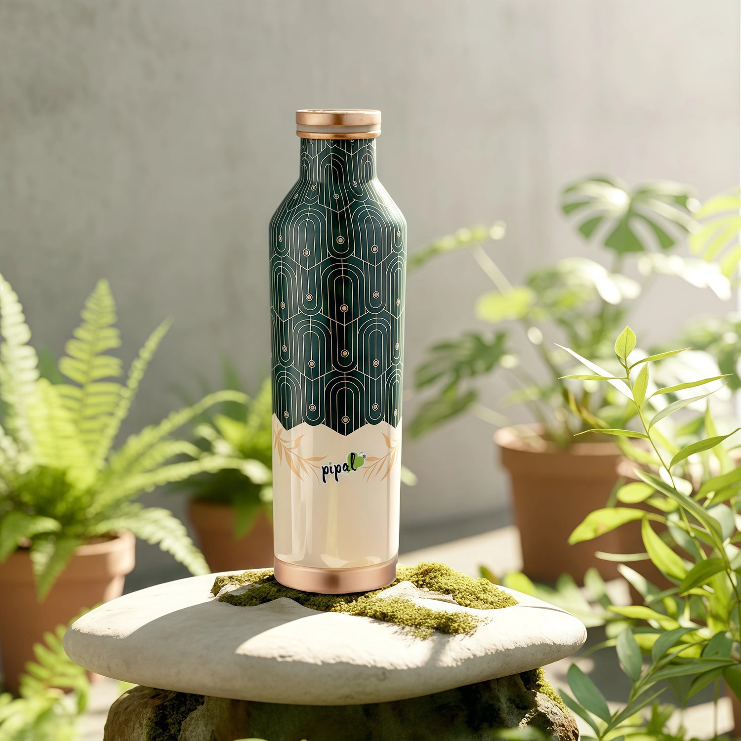 Green and copper water bottle with 'Pipal' branding on a stone surface with plants in the background