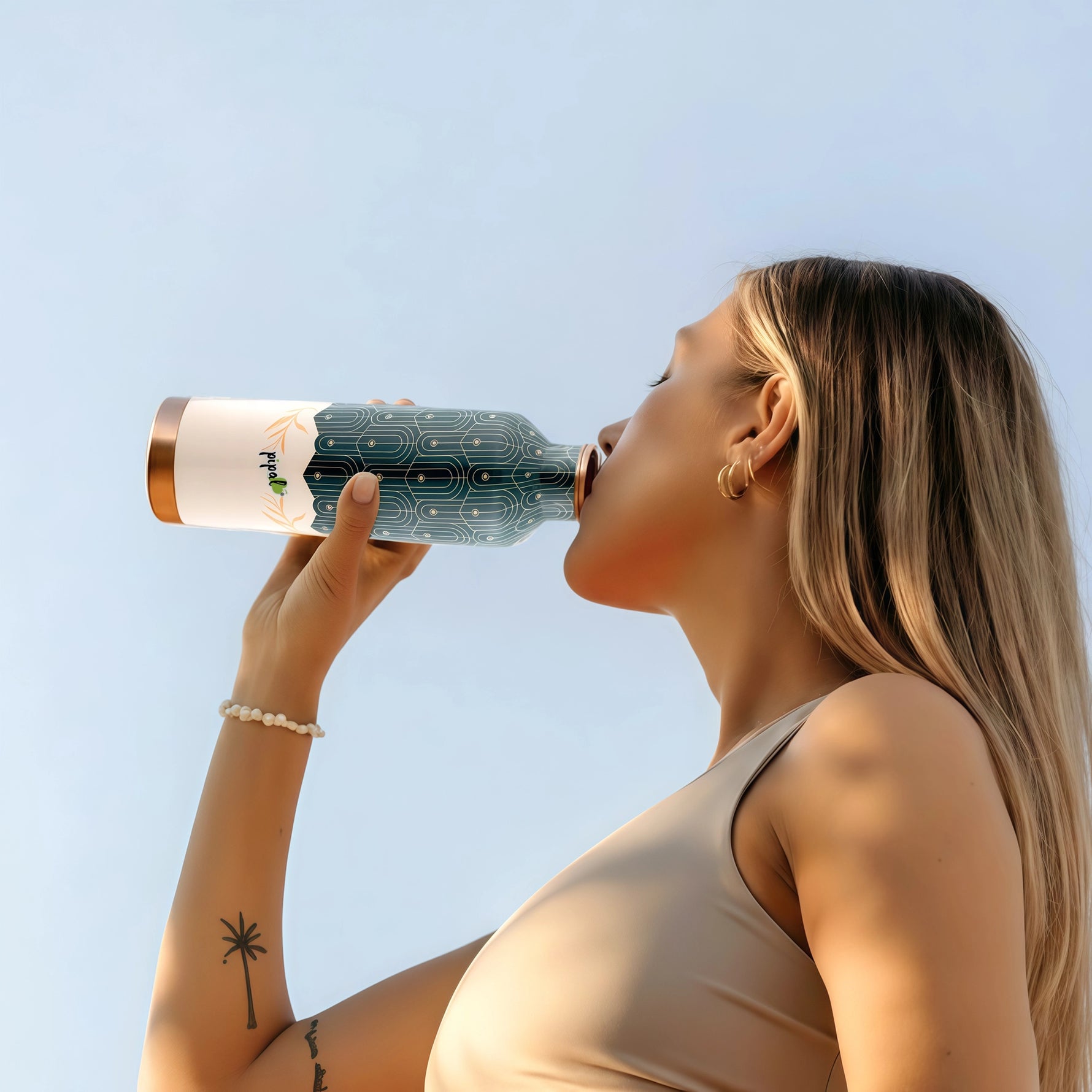Woman drinking from a copper bottle against a clear blue sky