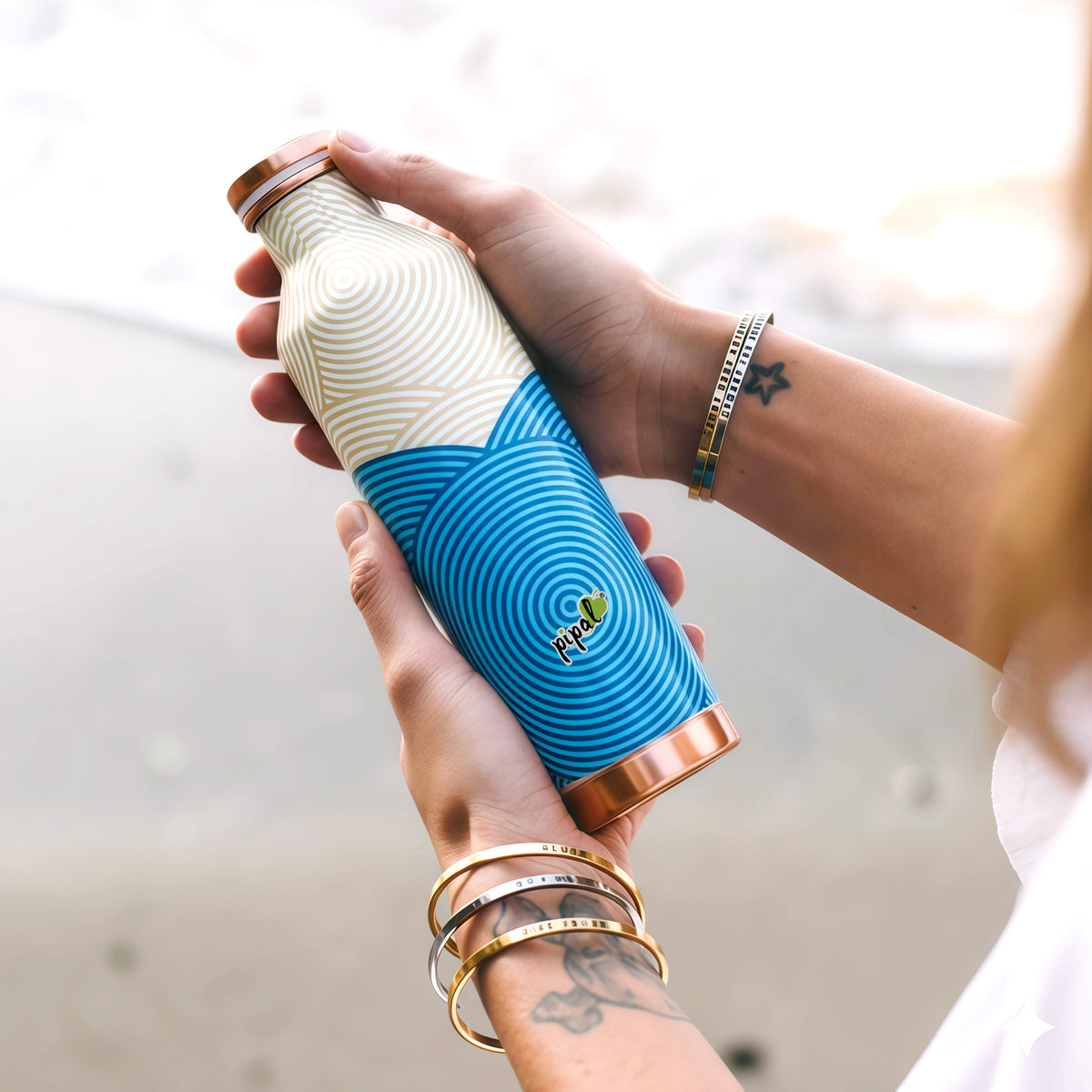 Person holding a blue and white textured copper bottle with pipal brand logo.